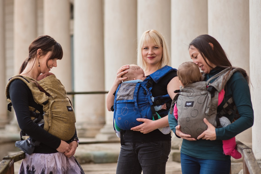 A group of happy mothers with small babies in baby carriers
